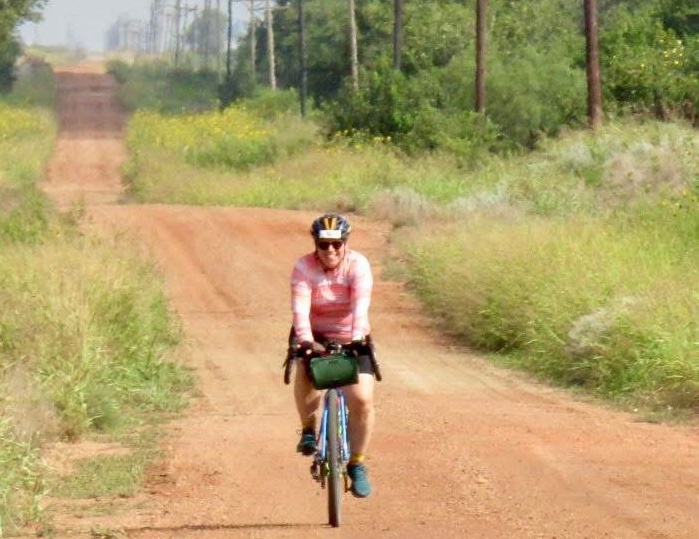 Priscilla biking down a red dirt road